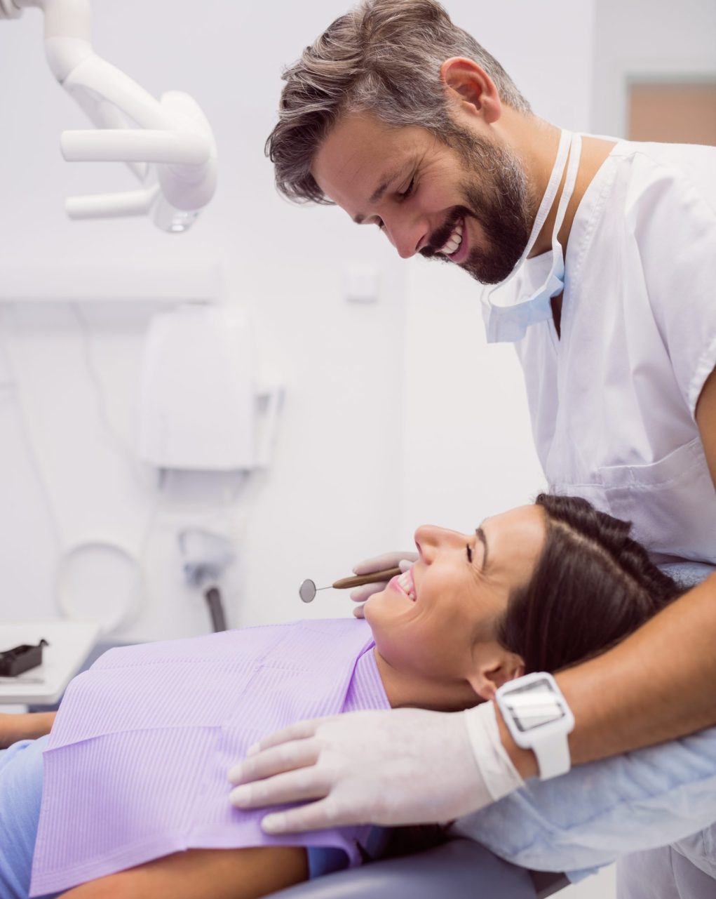 Dentist smiling while examining patient in clinic